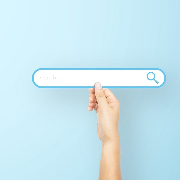 Hand holding paper with search bar on light blue background. Concept of searching information data on internet networking